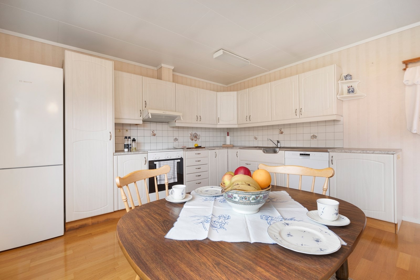 Kjøkkenet har hvit og tidløs utforming Galleribilde