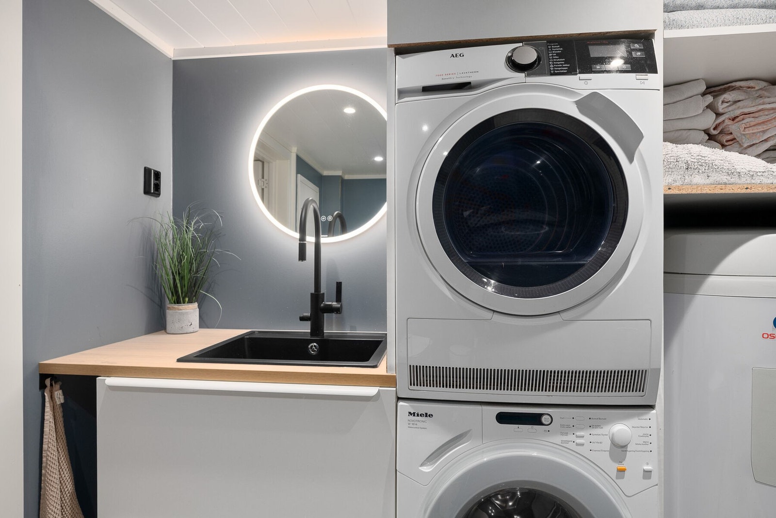 Bad/vaskerom fra 2020 med malte plater på vegg, våtromsplater i dusj og belegg på gulv med elektrisk gulvvarme. Det er lysspeil og spotbelysning i tak. Galleribilde