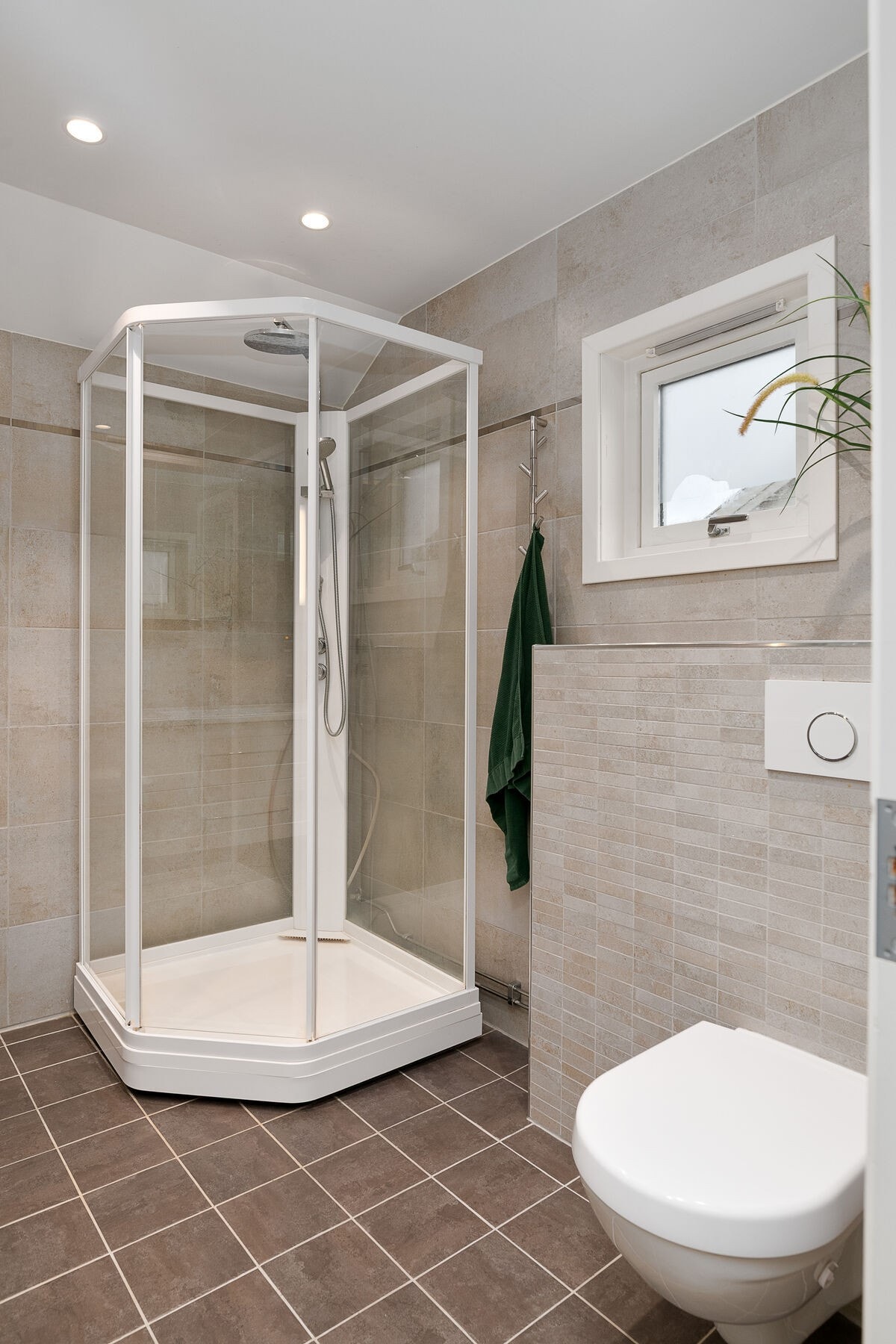 Badet har servant på innredning, lysspeil, dusjkabinett og veggmontert toalett. Galleribilde