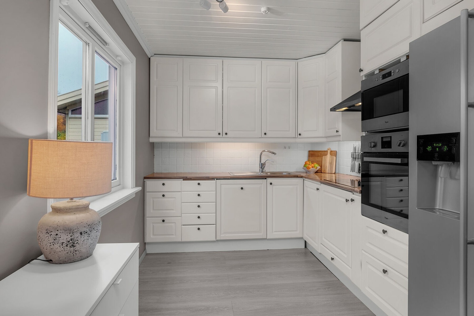 Kjøkkeninnredning med profilerte fronter, benkeplate, underskap og takhøye overskap. Galleribilde