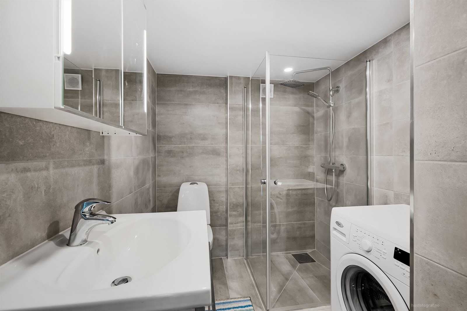 Innredet bad nr. 2 i underetasjen. Badet er delikat innredet med flislagte overflater, downlights i himling, toalett, servant, dusjhjørne og opplegg for vaskemaksin. Galleribilde