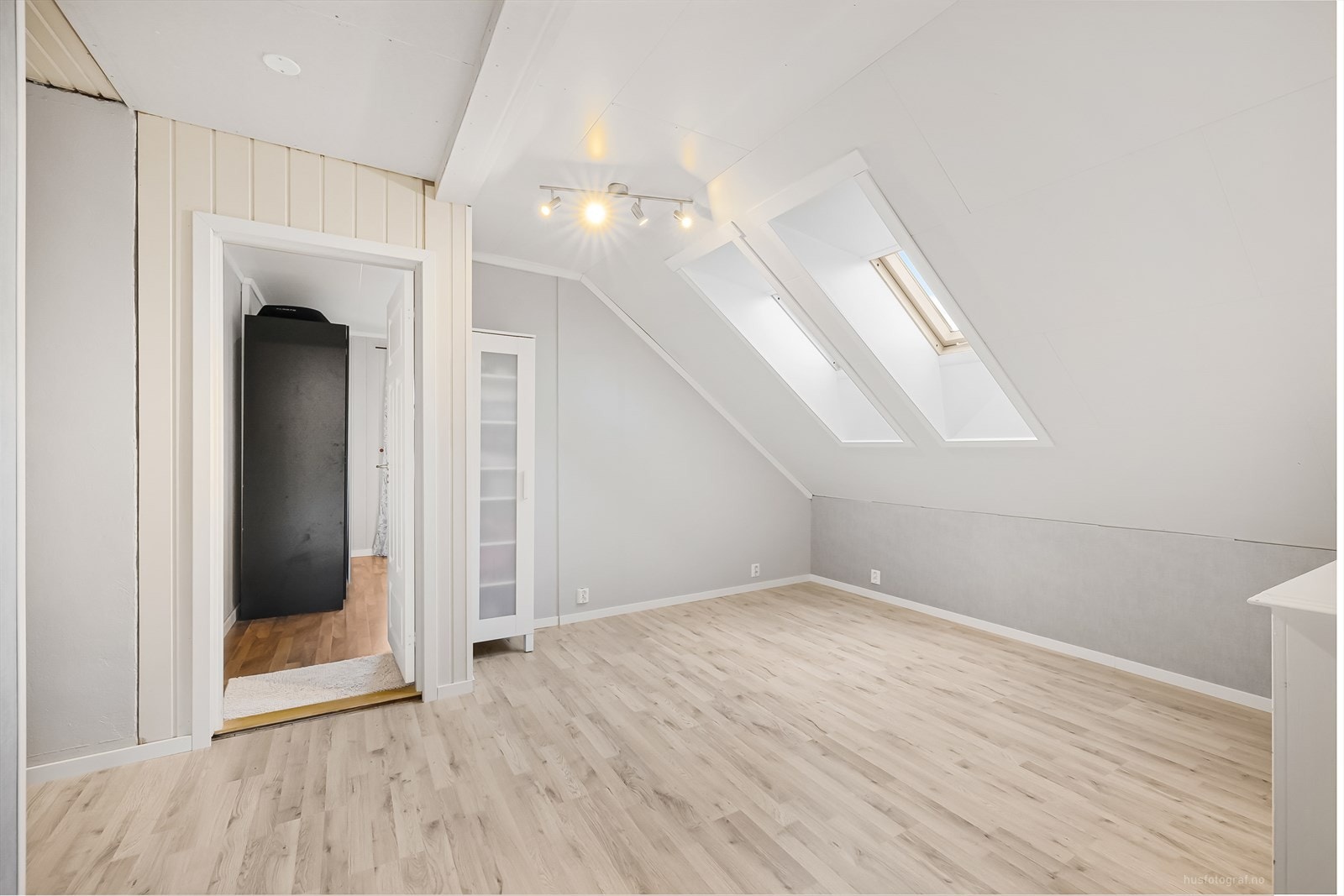 Loftstuen er lyst innredet med laminat på gulv og lysmalte overlater. Her er det plass til både sofa og tv. Galleribilde