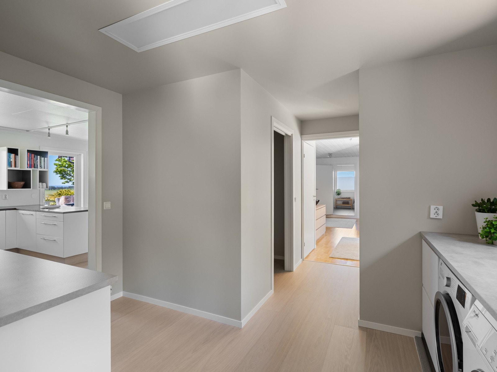 Rommet er innredet med hvite, slette fronter, god benkeplass og tilrettelagt for både vaskemaskin og tørketrommel under benk. Galleribilde