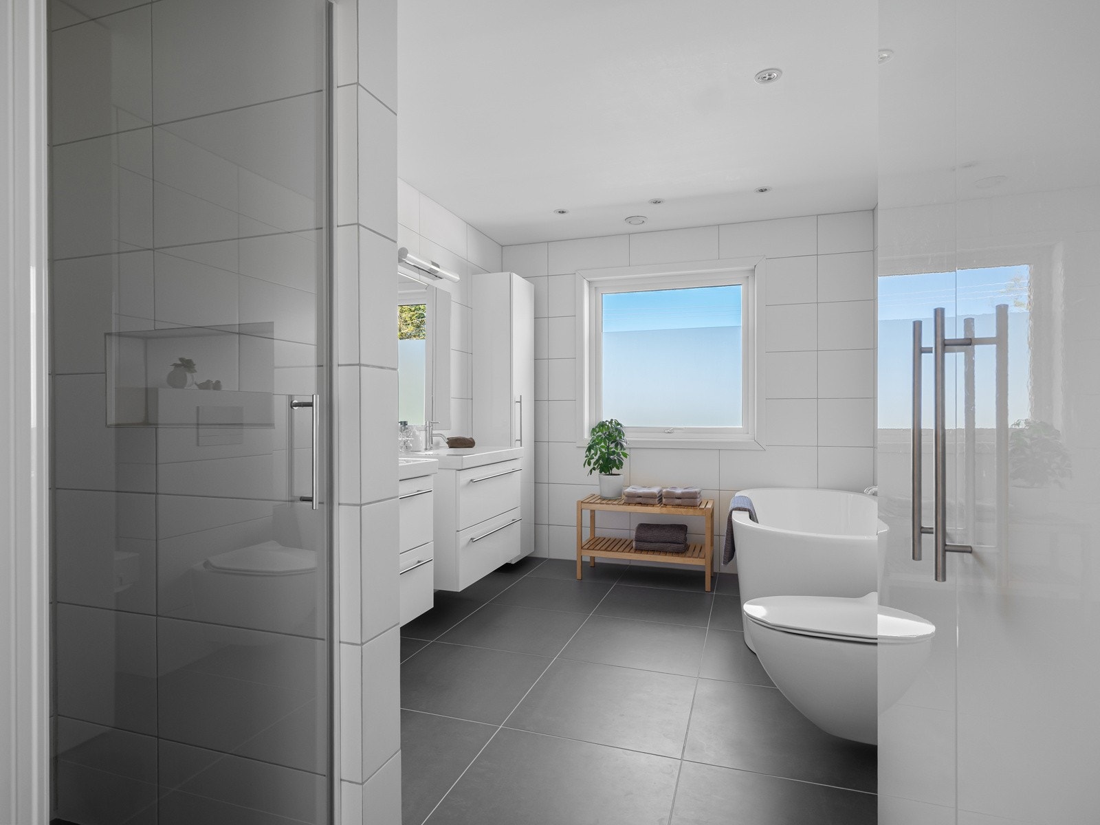 Lyst og romslig bad med helflisede overflater. Galleribilde