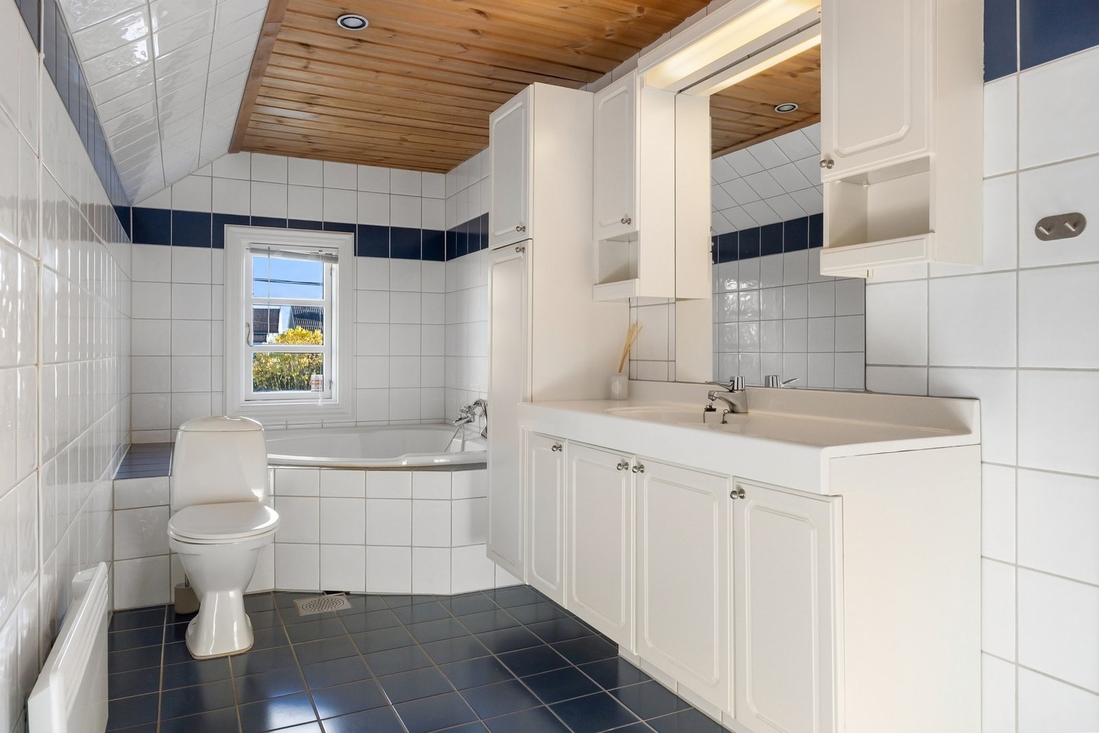 Baderommet har innmurt badekar, dusj, gulvstående toalett og opplegg for vaskemaskin og tørketrommel. Galleribilde