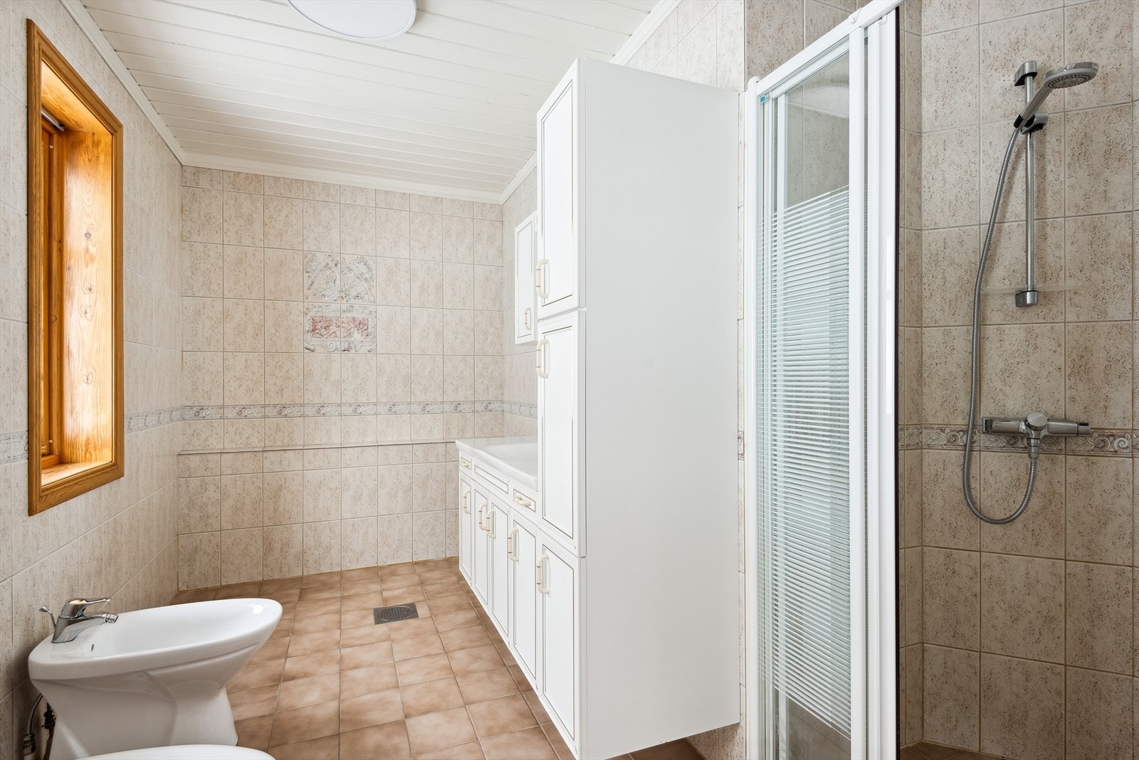 Badet har flistlagt gulv og vegger | Varme i gulv | Romslig vindu for innslipp av naturlig lys. Galleribilde