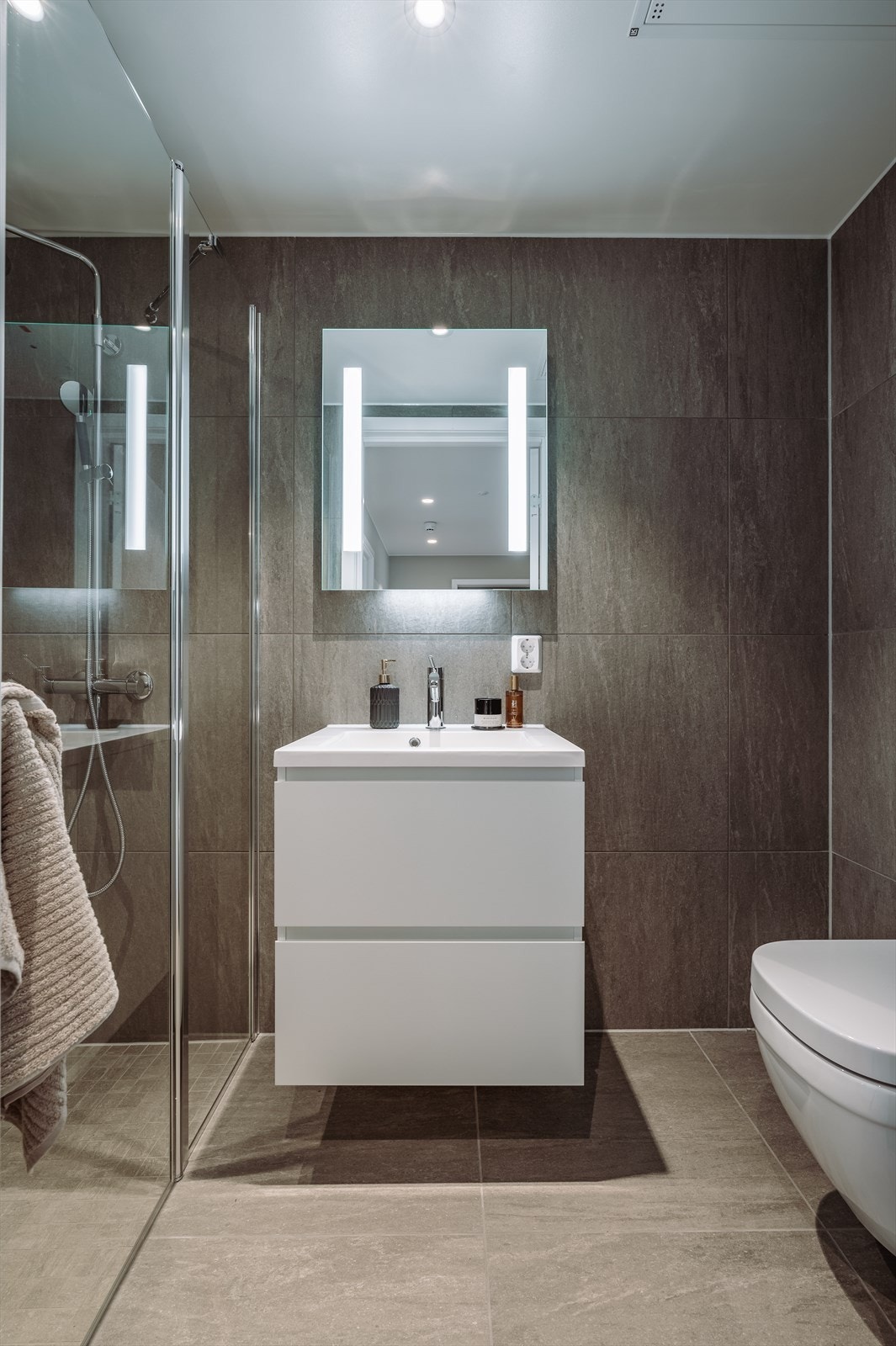 I denne leiligheten er badene levert med mørke og moderne fliser Galleribilde