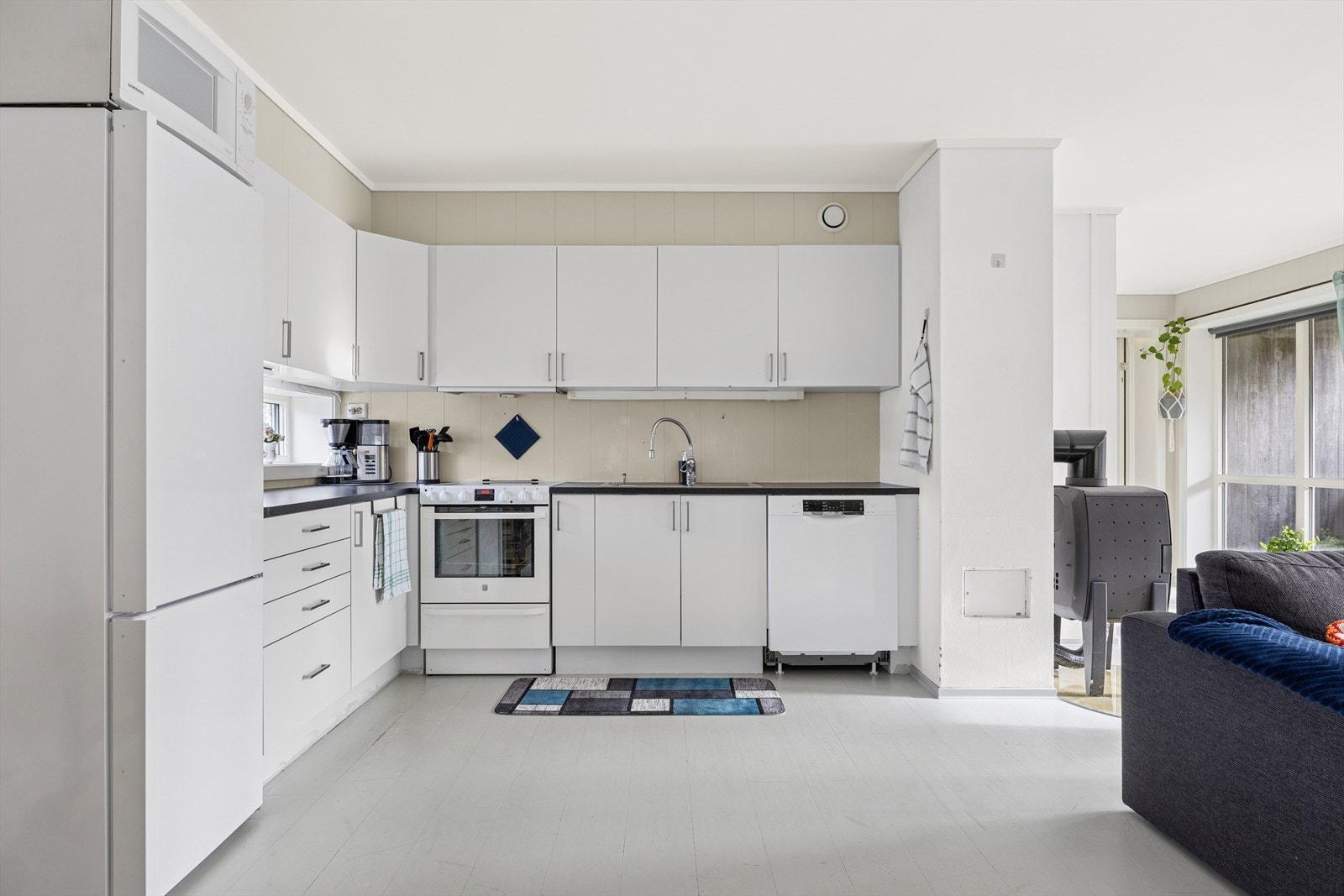 Kjøkkeninnredning med hvite slette fronter og mørk benkeplate. Galleribilde