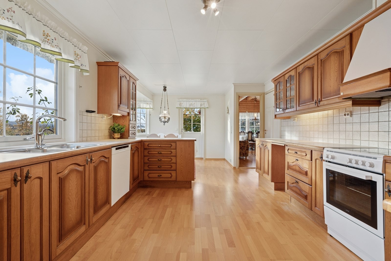 Kjøkkeninnredning med heltre, profilerte fronter, skap og god benkeplass. Laminert benkeplate med dobbel stålvask og fliser på vegg over benk. Galleribilde