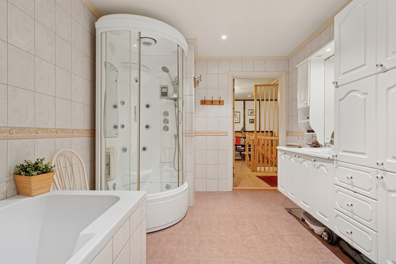 Badet er utstyrt med heldekkende servant over innredning, to overskap, speil med lys, to høyskap, dusjkabinett med styrt avløp til sluk, vegghengt toalett og badekar. Galleribilde