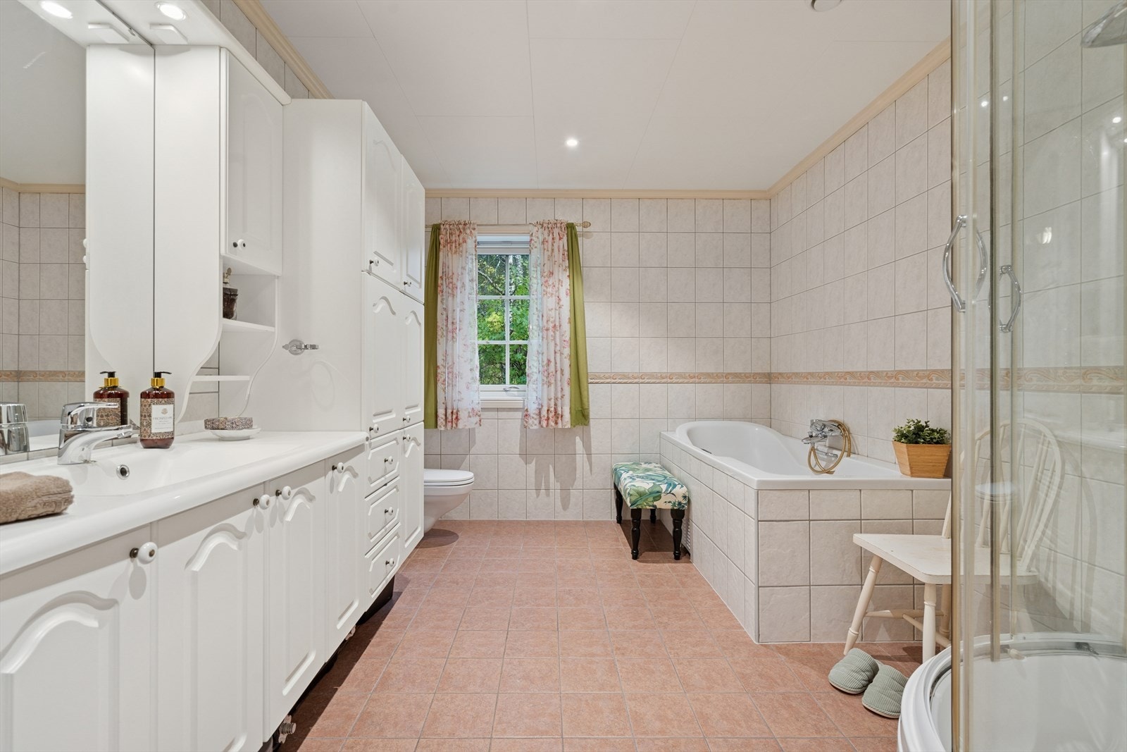 Badet er fra byggeår og har flislagt gulv med nedstøpte, elektriske varmekabler. Veggene er flislagte og det er malte himlingsplater i himling. Galleribilde