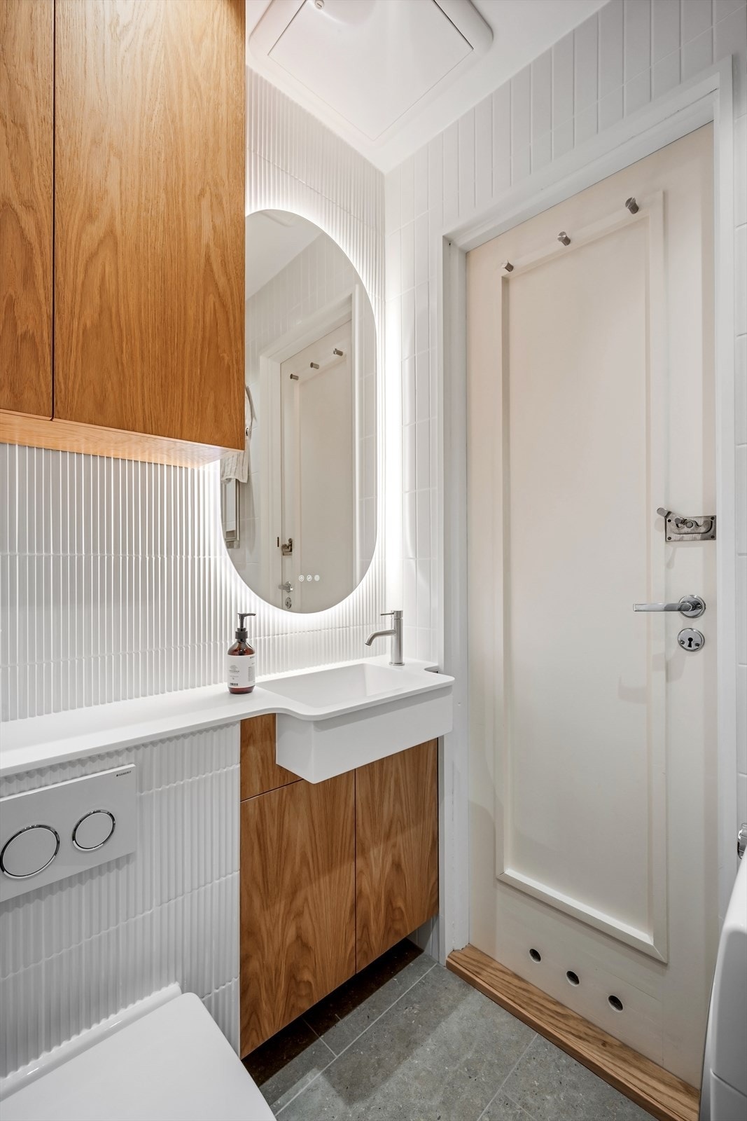 Rommet inneholder dusjhjørne med innfellbare glassdører og hånd- og regndusj, veggmontert toalett og baderomsinnredning med overlimt servant med ettgreps armatur fra Tapwell og speil på vegg med integrert belysning. Galleribilde