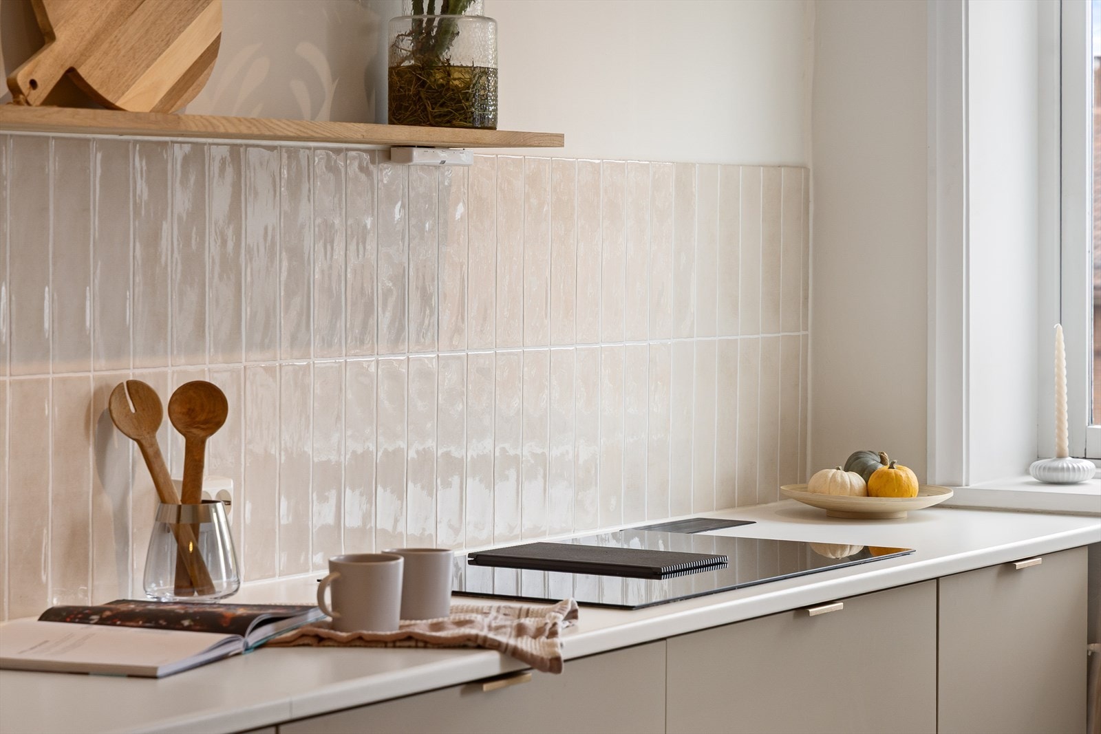 Tidsriktig innredning med glatte fronter, fliser på veggen over kjøkkenbenk og benkeplate i laminat. Galleribilde