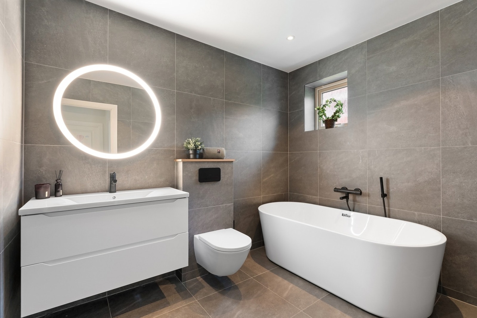 Utstyrt med stilfulle 60x60 fliser, badekar og vegghengt toalett Galleribilde