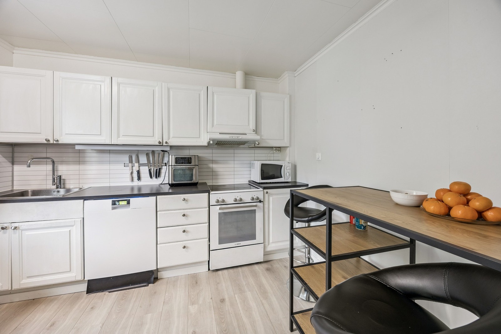 Kjøkkenet har lys innredning med profilerte fronter og benkeplate av laminat Galleribilde