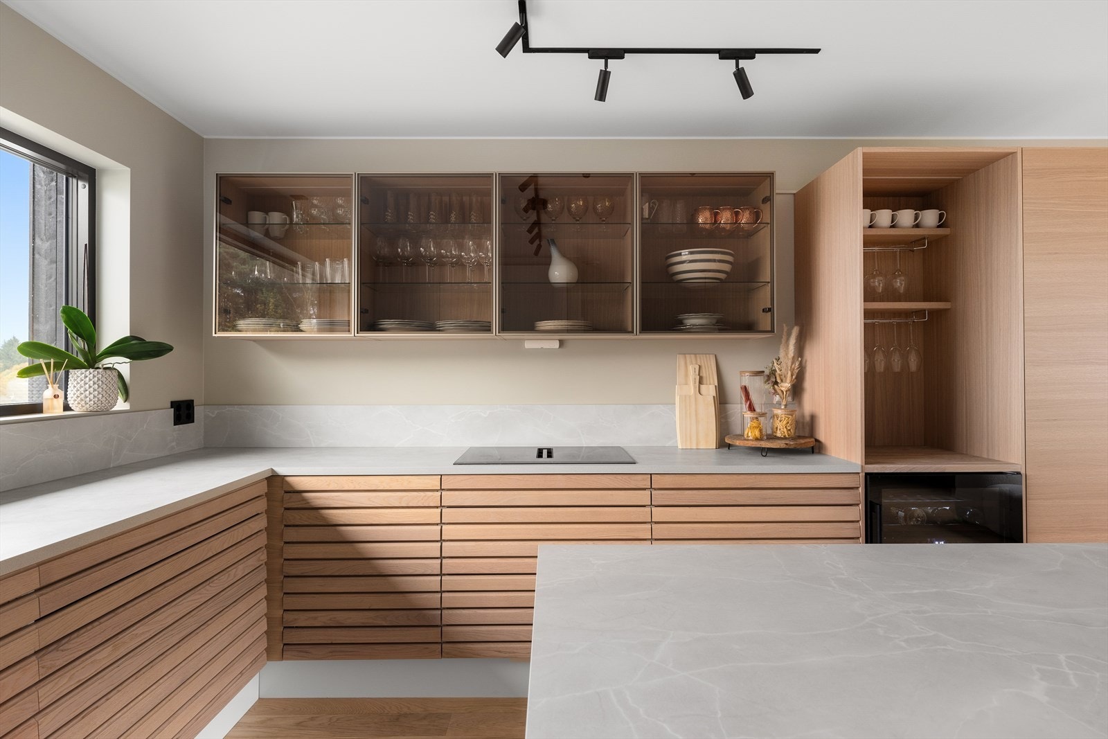 Eksklusive spilefronter i eik, kombinert med glassfronter og rene, hvite matte flater, gir kjøkkenet et uttrykk av tidløs kvalitet og karakter. Galleribilde