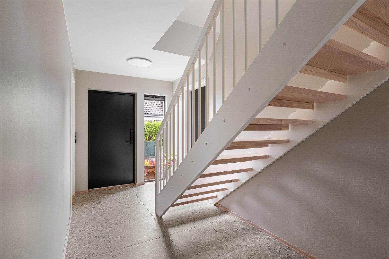 Lys og romslig entré med lekre fliser og åpen trappeløsning i tre. Galleribilde