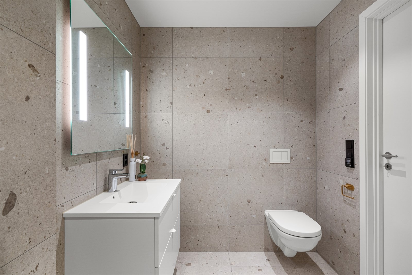 Badet i 1. etasje er i samme utførelse som badet i 2. etasje. Badet er innredet med servant med underskap, speil med belysning, vegghengt toalett og dusjhjørne. Galleribilde