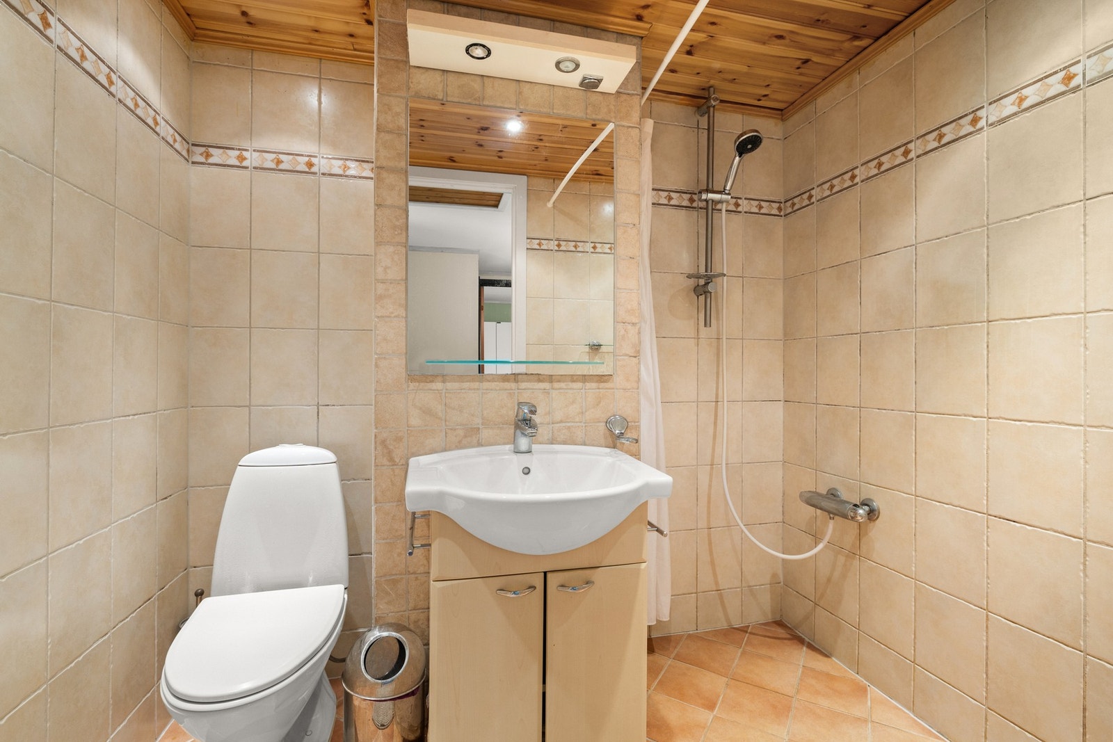 Badet i overetasjen er flislagt, og er innredet med dusj, servantinnredning og toalett Galleribilde