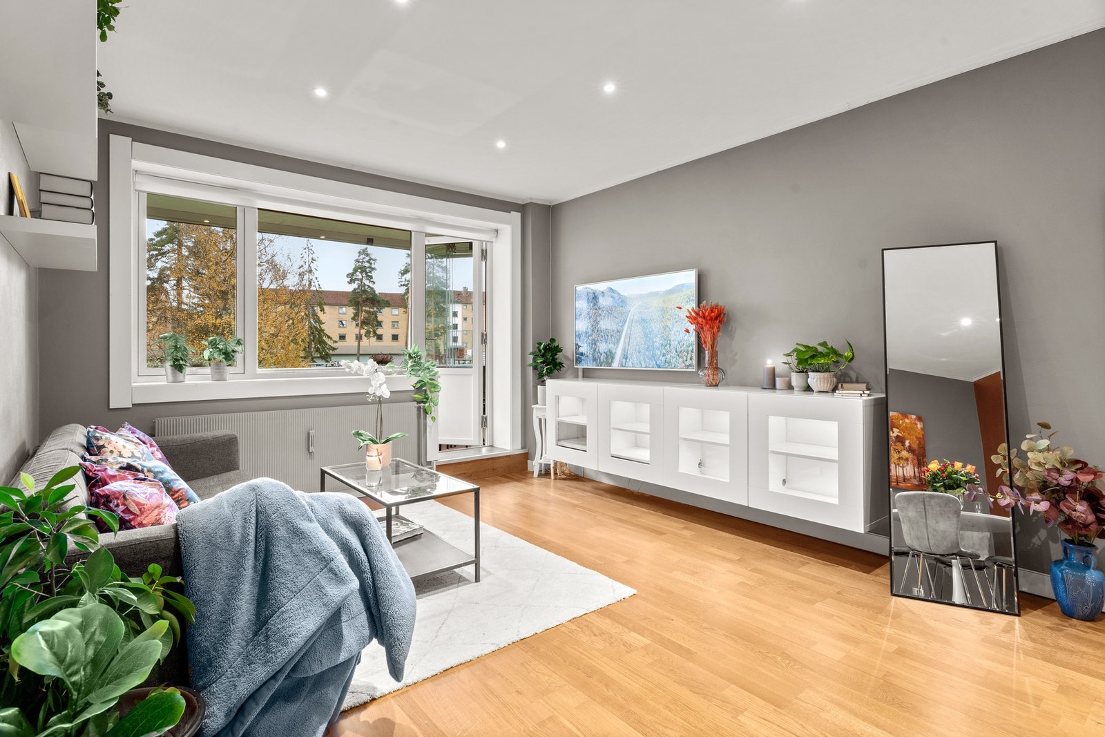 Stuen får godt med naturlig lysinnslipp fra store vindusflater. Vinduene og balkongdøren ble skiftet i regi av borettslaget i 2014. Galleribilde