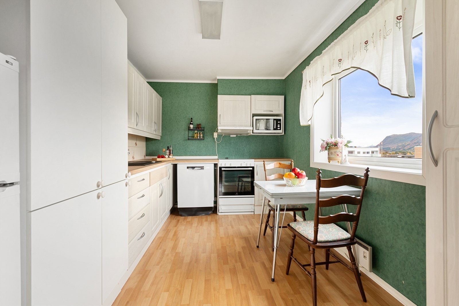 Kjøkken med god skapplass og spiseplass ved vinduet. Galleribilde