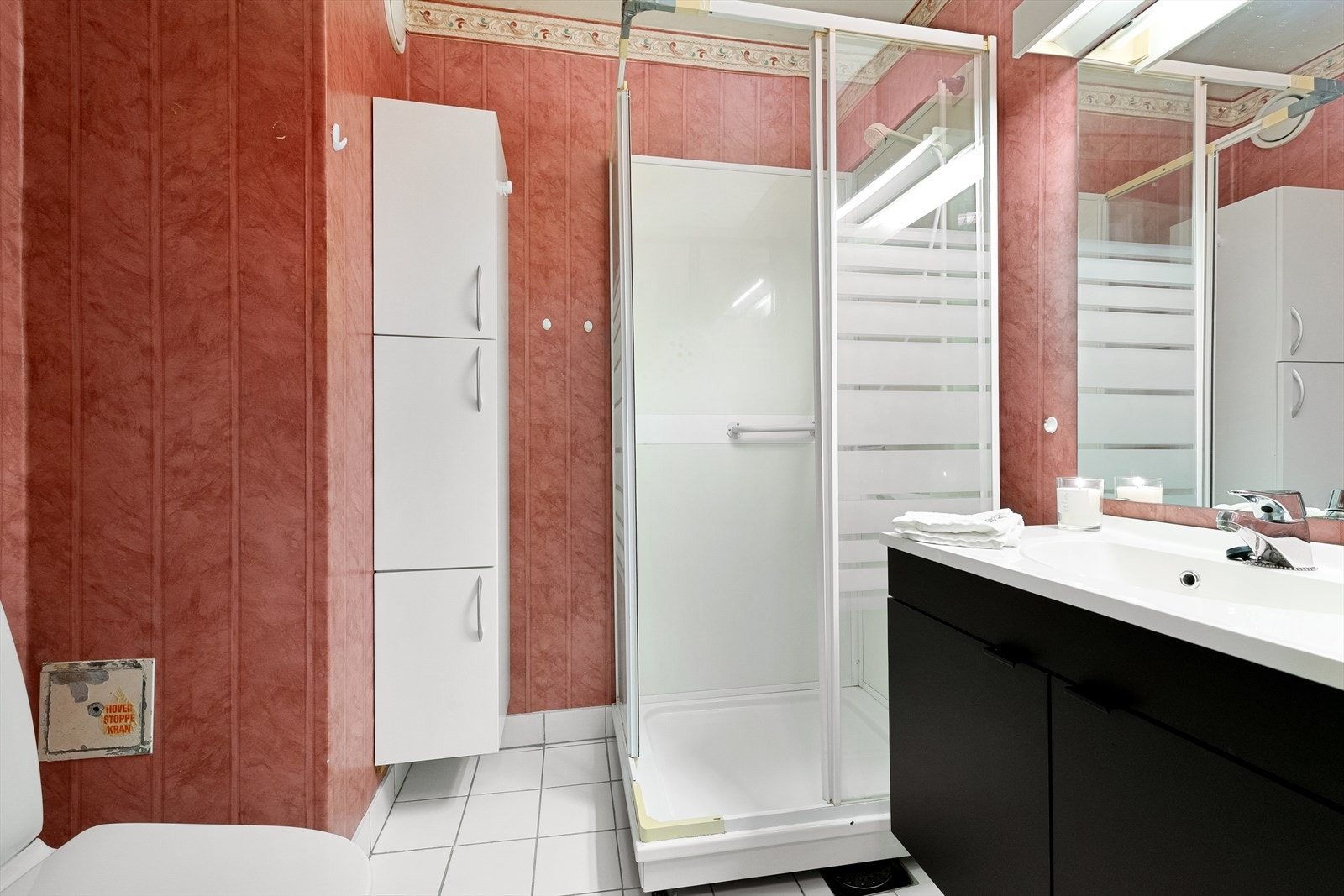 Bad ligger vegg i vegg med vaskerom. Rommet har innredning med servant, dusjkabinett og wc. Galleribilde