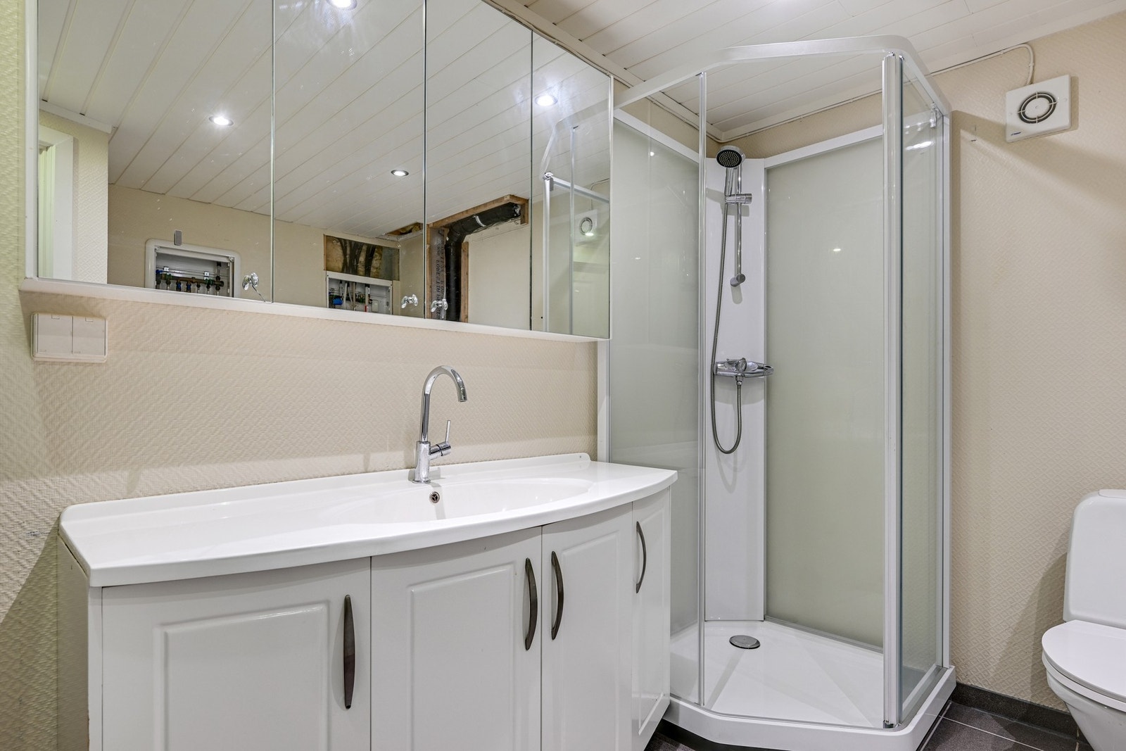 Et romslig bad med både dusjkabinett, servant, skyllekum og opplegg for vasmaskemaskin Galleribilde