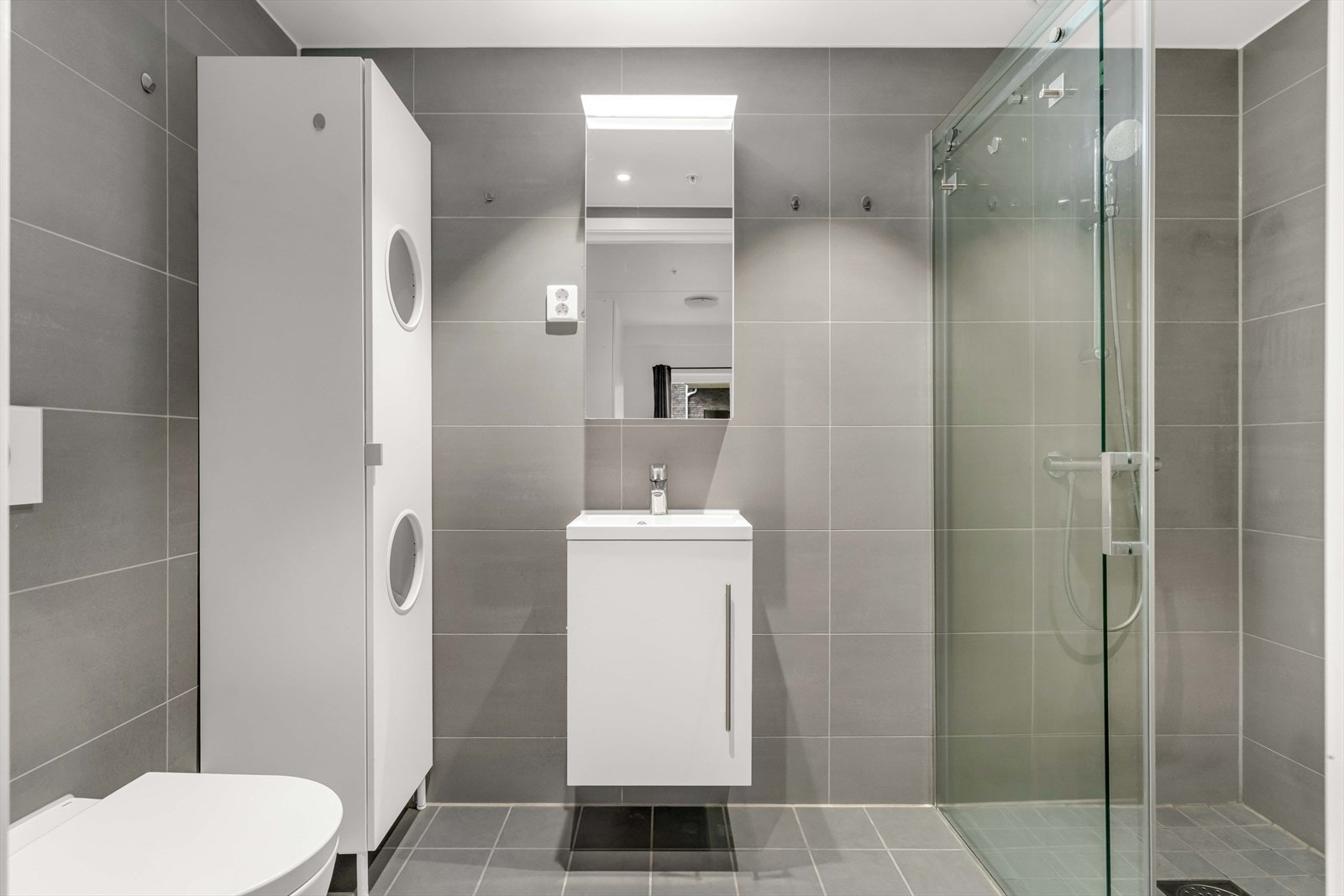 Badene har lik utførelse med grå, flislagte overflater, varme i gulvet og innfelte downlights i himling. Galleribilde