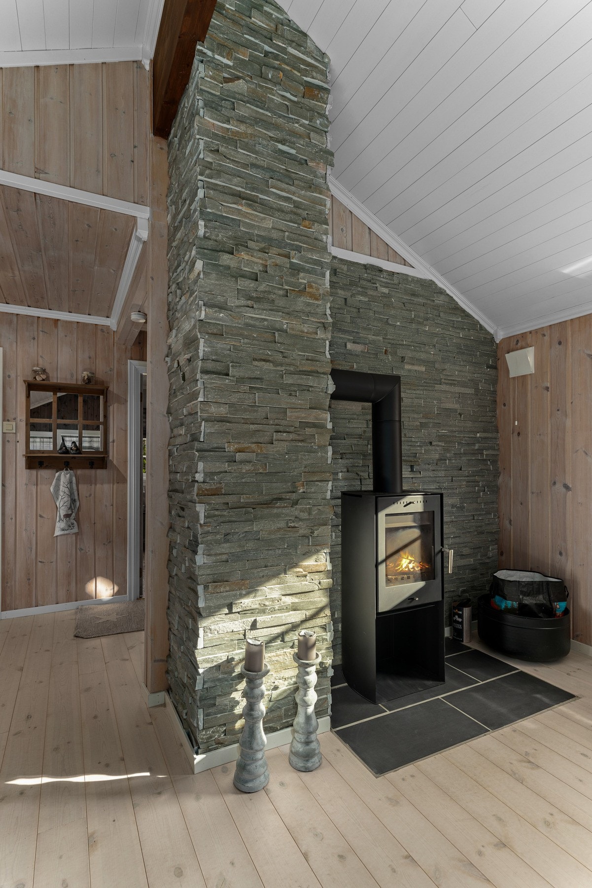 I rommet står en moderne vedovn med flott natursteinsinnramming, som fungerer som et naturlig midtpunkt og gir god varme på kalde dager. Galleribilde