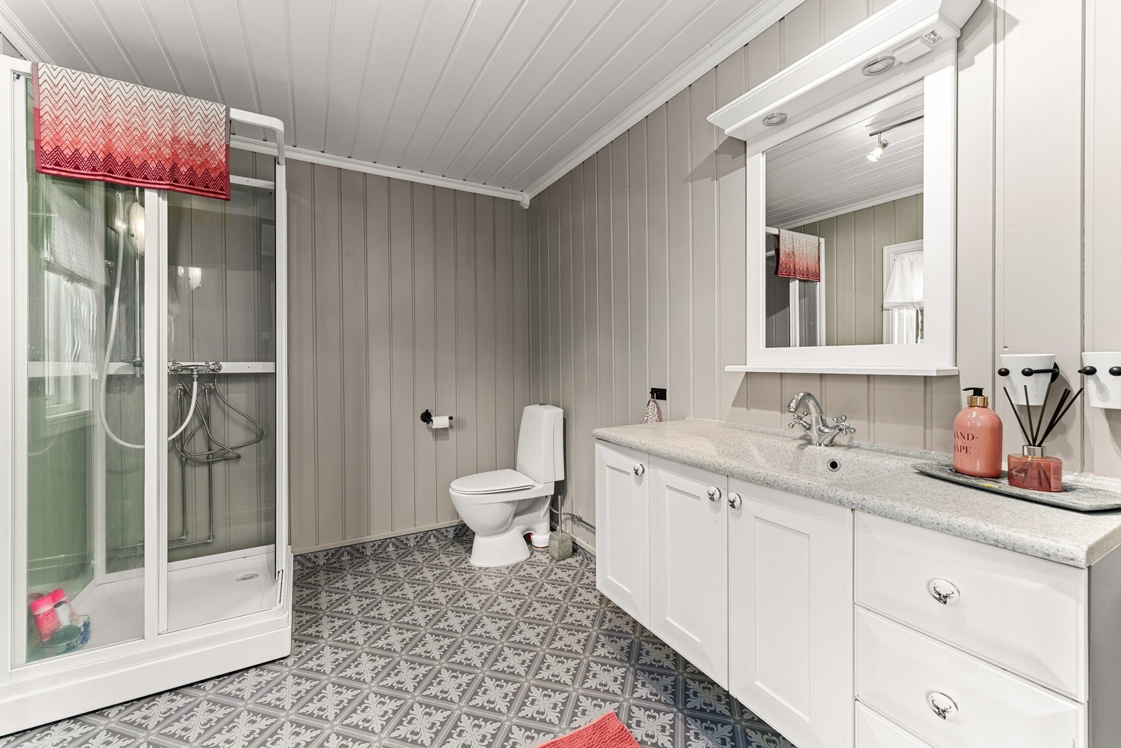 Det romslige badet fremstår som lyst, innbydende og praktisk. Her er det gulvbelegg med oppbrett, som gir et lettstelt og fuktsikkert underlag, kombinert med malt panel på vegger og i himling. Galleribilde