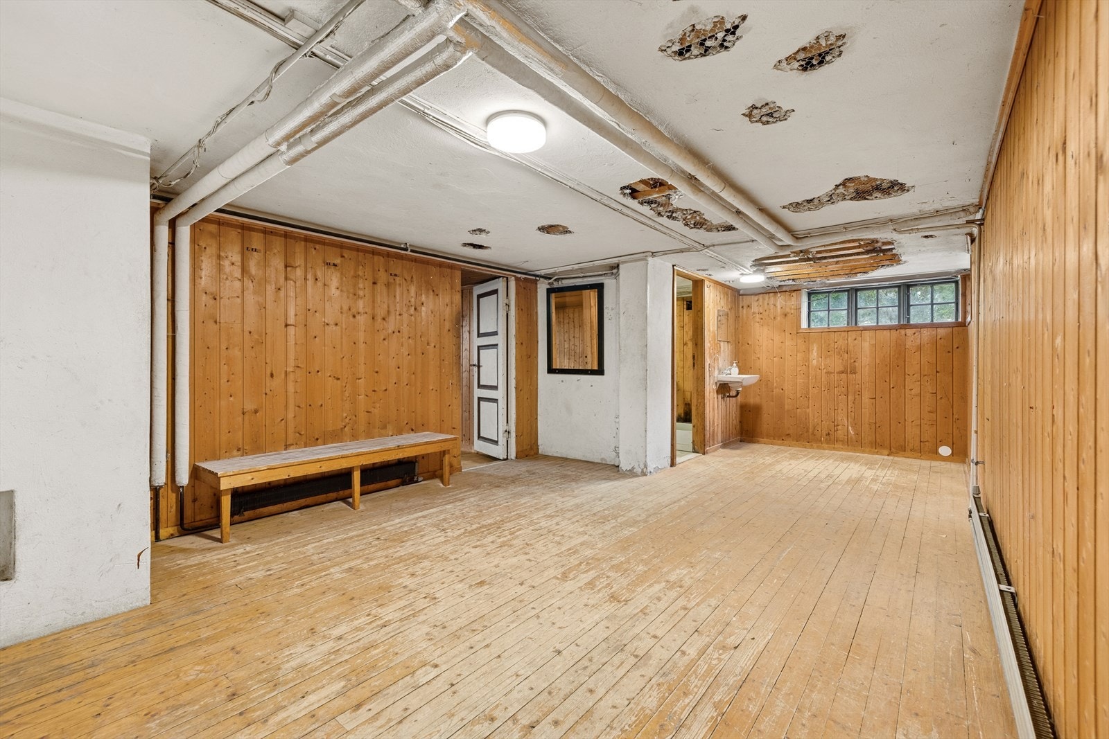 Romslig kjellergang med tregulv og panelte vegger - et rom som byr på mange muligheter for den som ønsker å oppgradere og utnytte arealet fullt ut. Galleribilde