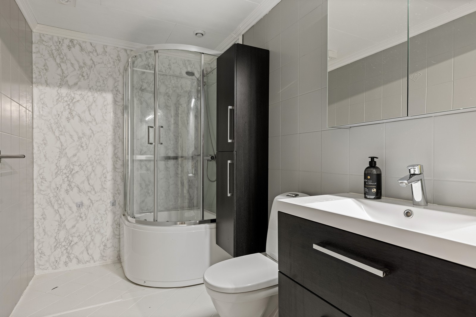 Bad fra byggeår i underetasjen med dusjkabinett, toalett samt servantinnredning. Galleribilde