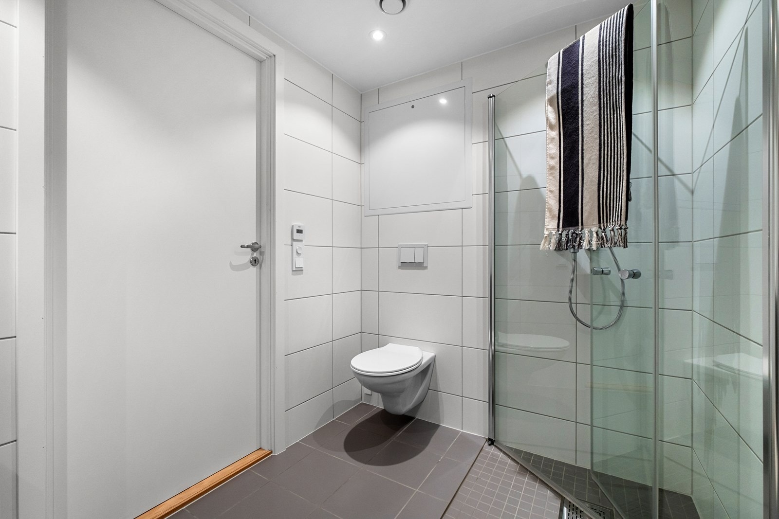 Badet byr på veggmontert innredet servant og toalett, opplegg for vaskemaskin samt praktiske innfellbare dusjdører. Det medfølger leiligheten. Galleribilde