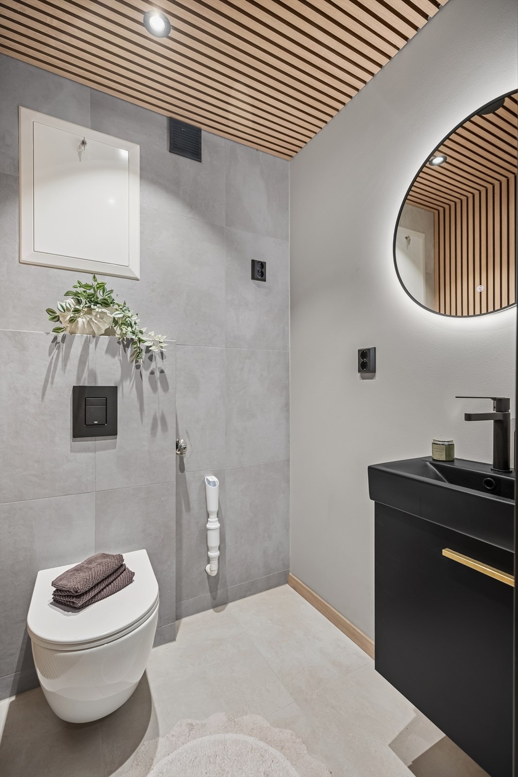 Toalettrom med vegghengt toalett og servant med slette fronter.
Flislagt gulv. Fliser, spiler og slette vegger. Spiler i himling med
downlights. Opplegg for vaskemaskin på rommet. Galleribilde