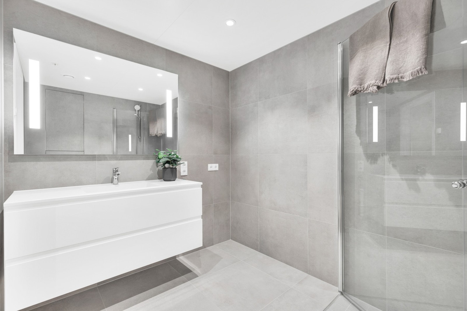 Rommet er utstyrt med dusjhjørne med innfellbare glassdører, vegghengt toalett, romslig baderomsinnredning og opplegg for vaskemaskin. Galleribilde