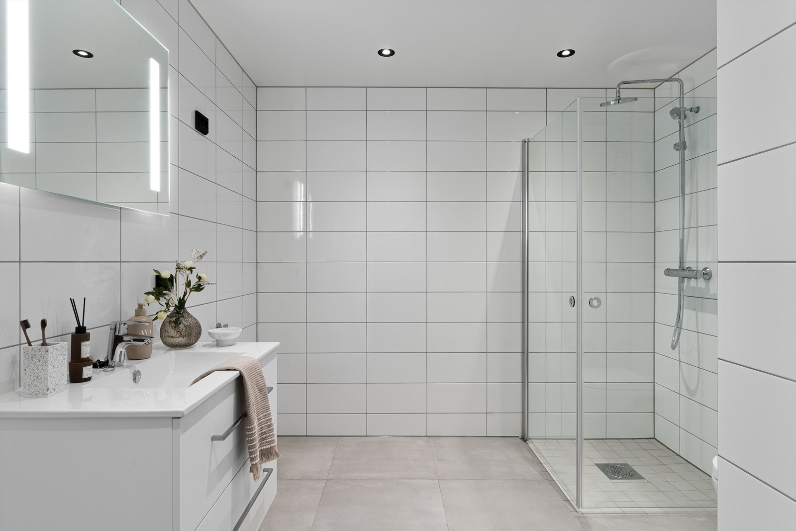 Badet fremstår som arealeffektivt med pen baderomsinnredning i hvit utførelse. Opplegg for vaskemaskin og tørketrommel kan også nevnes. Galleribilde