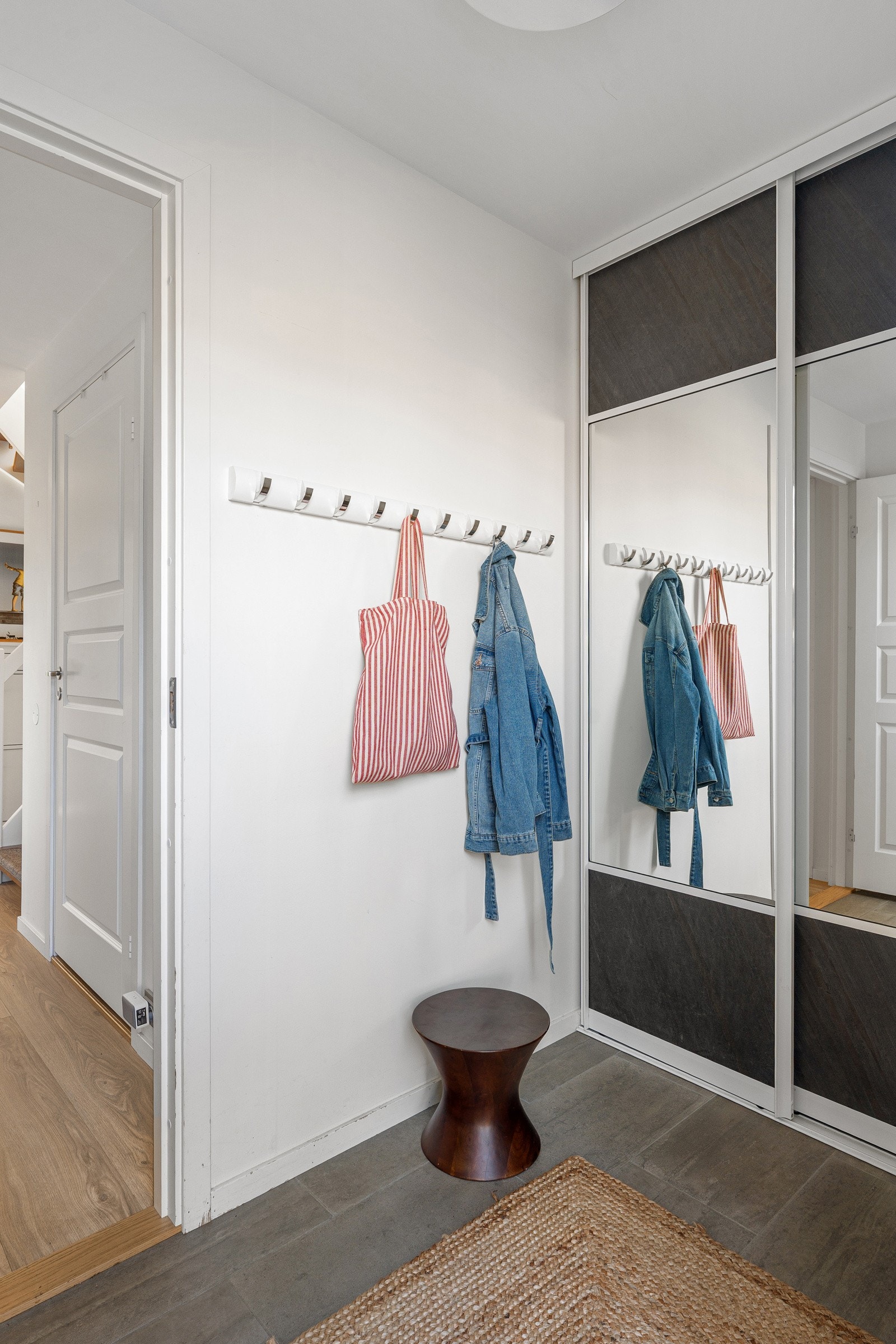 Innbydende entré med fliser på gulv, gulvvarme og skyvedørsgarderobe