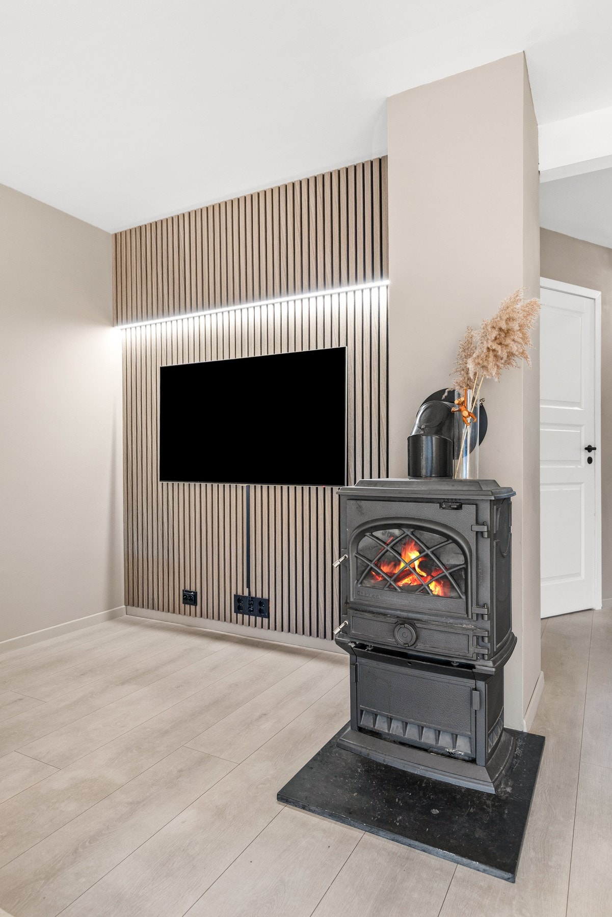 Boligen har lekre detaljer som spilevegg med LED list og en koselig peis for kaldere kvelder Galleribilde