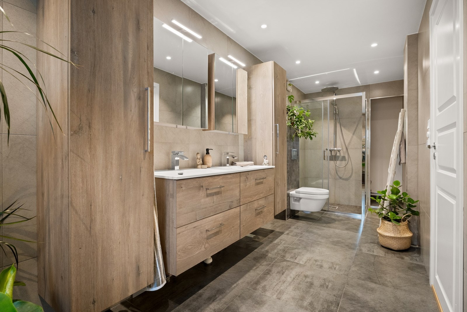 Delikat og romslig baderom med dusjnisje, moderne servant med underskap og stilrent toalett - alt i lyse og behagelige farger. Galleribilde