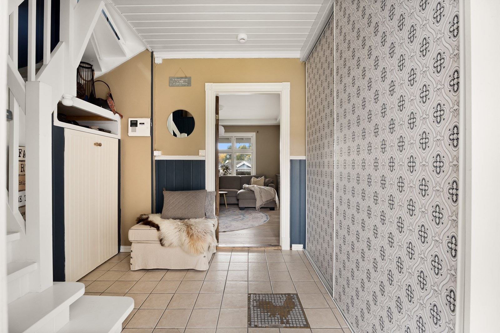 Mye av boligens historikk og sjarm er bevart i dette rommet og trappa. Legg feks merke til mosaikk-hanen på gulvet. Lagringsplass under trappa er også en del av en plassbygd løsning som bærer preg av eiendommens historikk Galleribilde