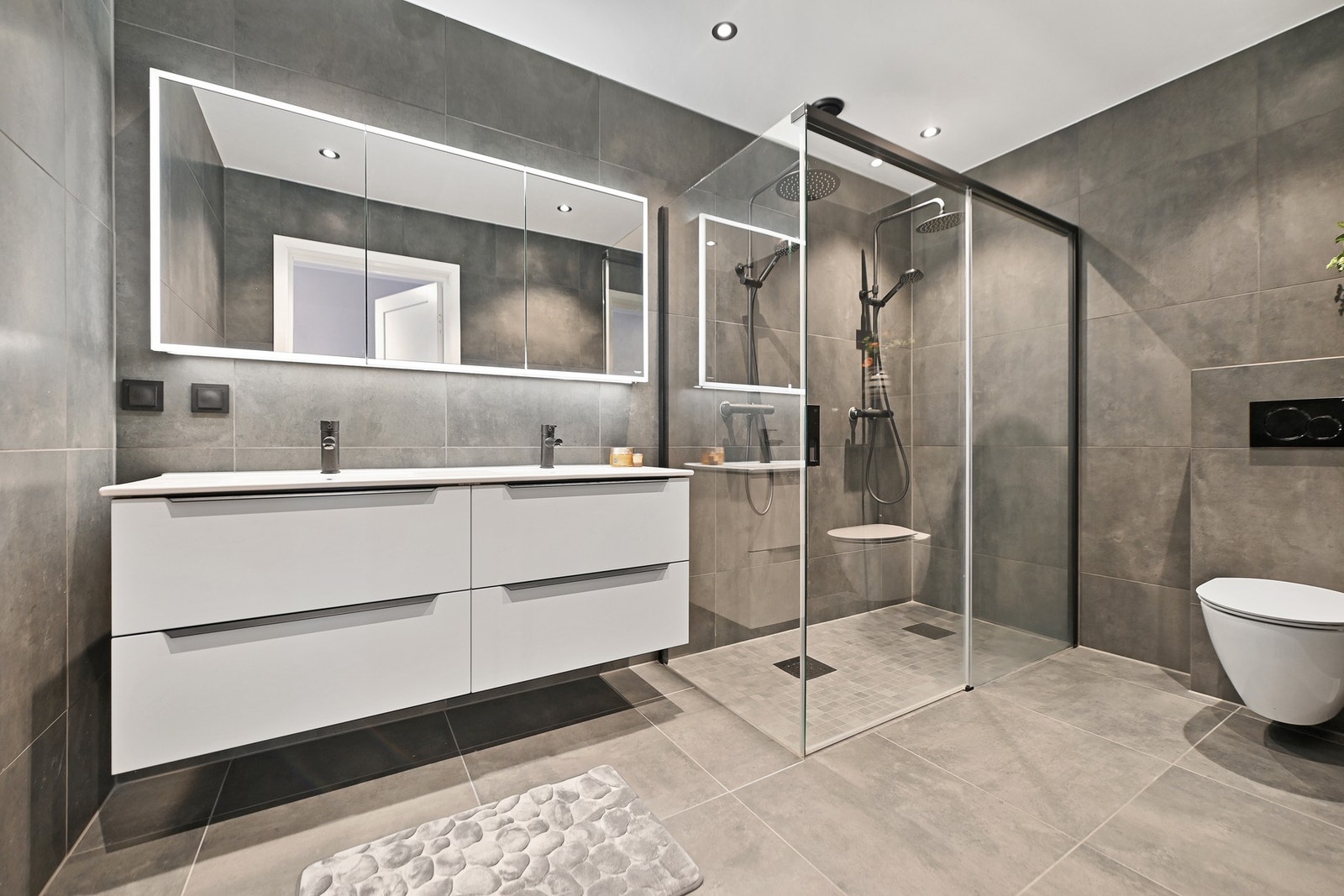 Boligen har to delitake bad, ett i hver etasje. Badet i 1. etasje er innredet med to nedfelte servanter, veggfestet toalett og dusjhjørne. Galleribilde