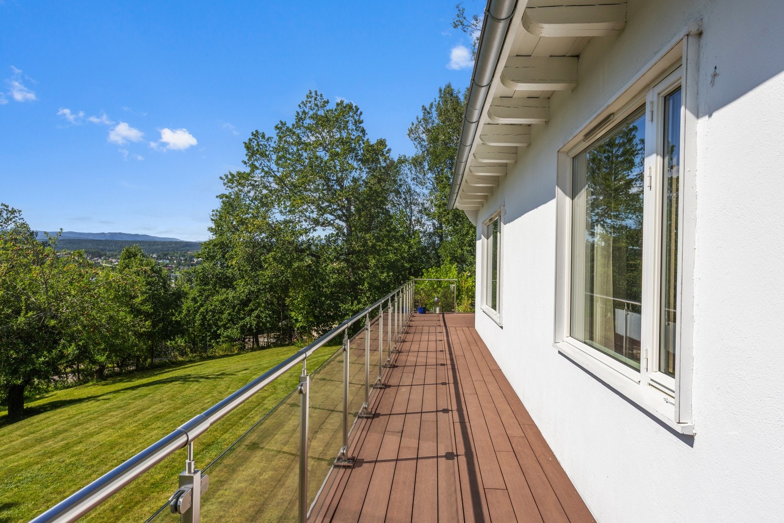 Stor solrik sørvestvendt terrasse som går foran hele fasaden med utgang fra stuen og kjøkkenet Galleribilde