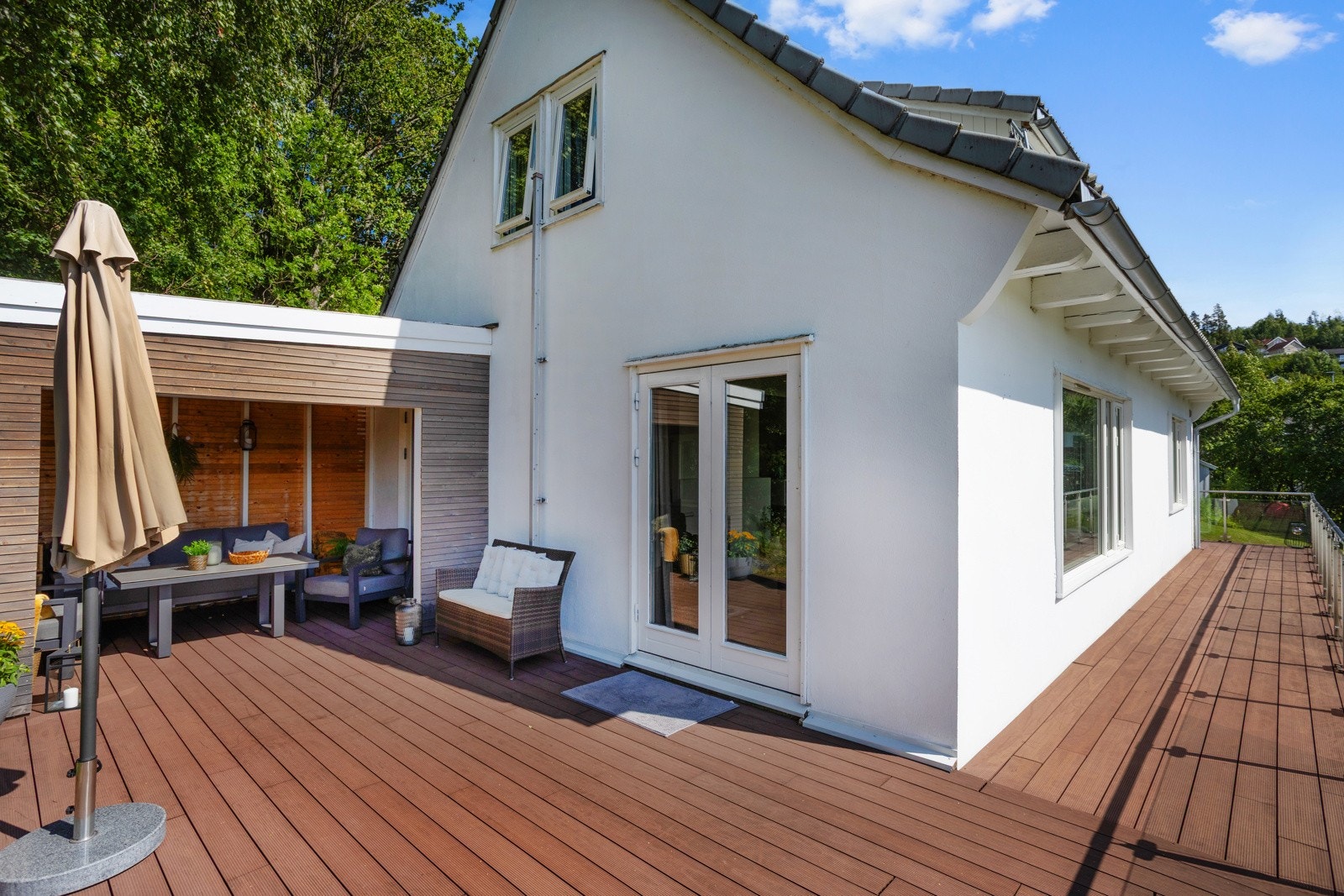 Stor sørvestvendt nyere terrasse i kompositt, syrefast stål (AISI316) og herdet sikkerhetsglass utenfor stuen og kjøkkenet Galleribilde