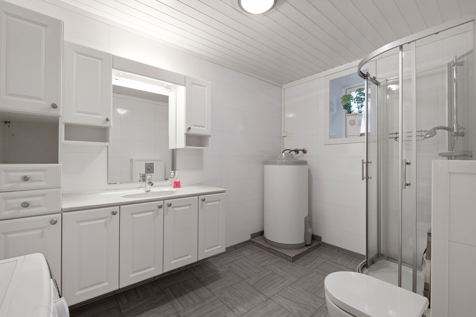 Lyst bad med baderomsplater på vegger og fliser med varmekabler i gulvet. Galleribilde