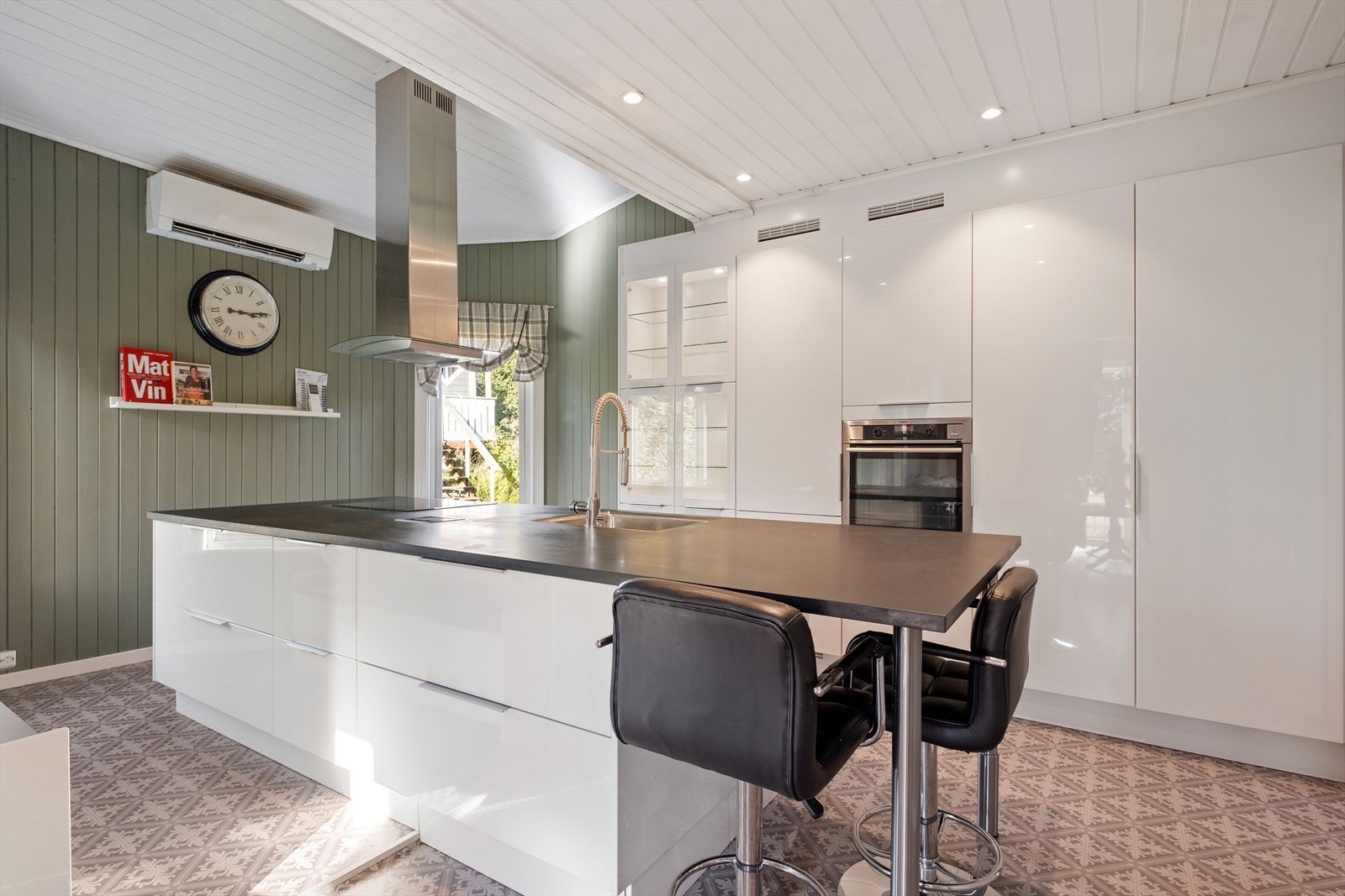 Kjøkkenet har høyskap og kjøkkenøy med glatte fronter, benkeplate av laminat og vask. Galleribilde