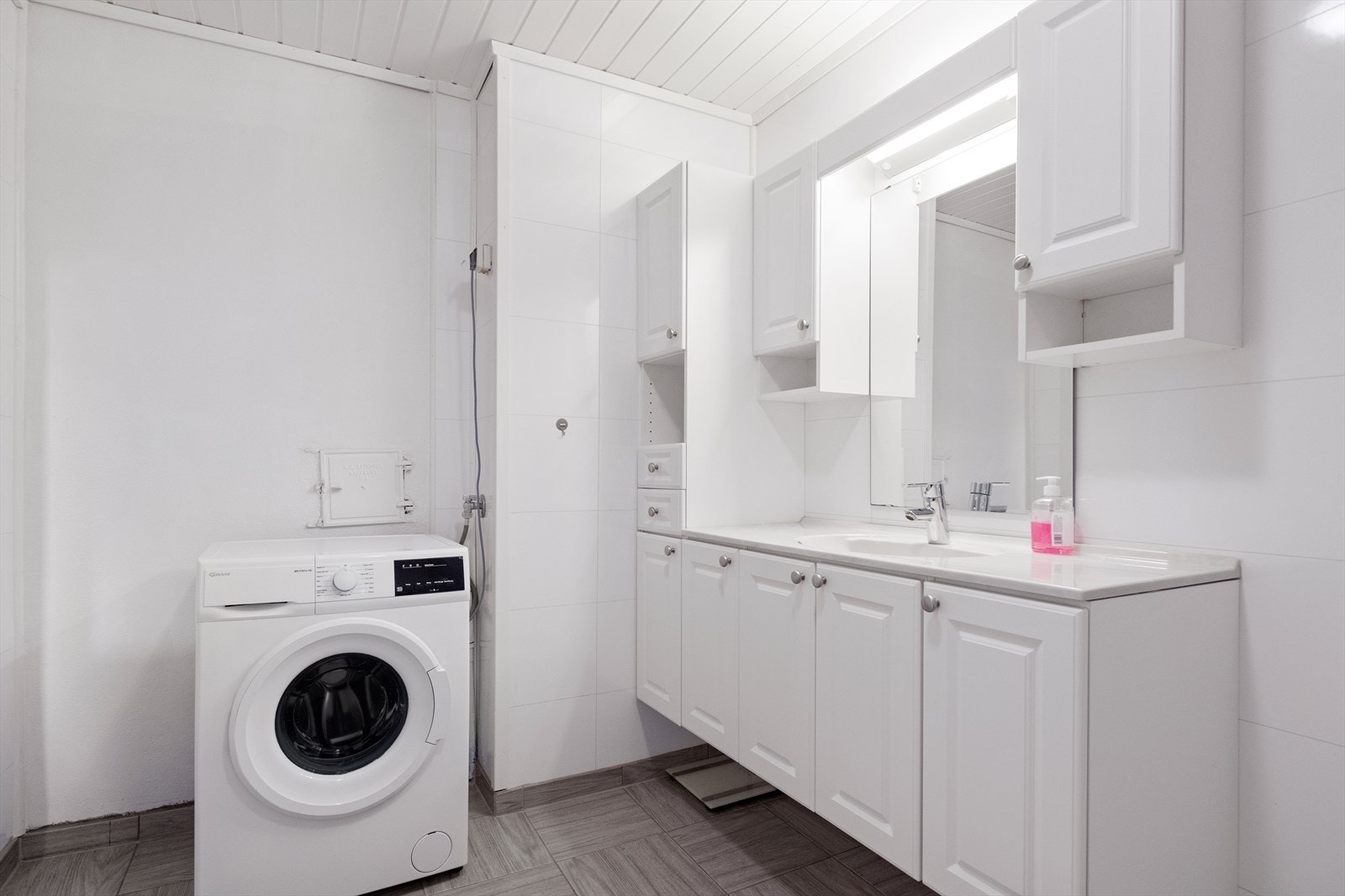 Rommet har innredning med nedfelt servant, veggmontert toalett, dusjkabinett, varmtvannsbereder og opplegg for vaskemaskin. Galleribilde