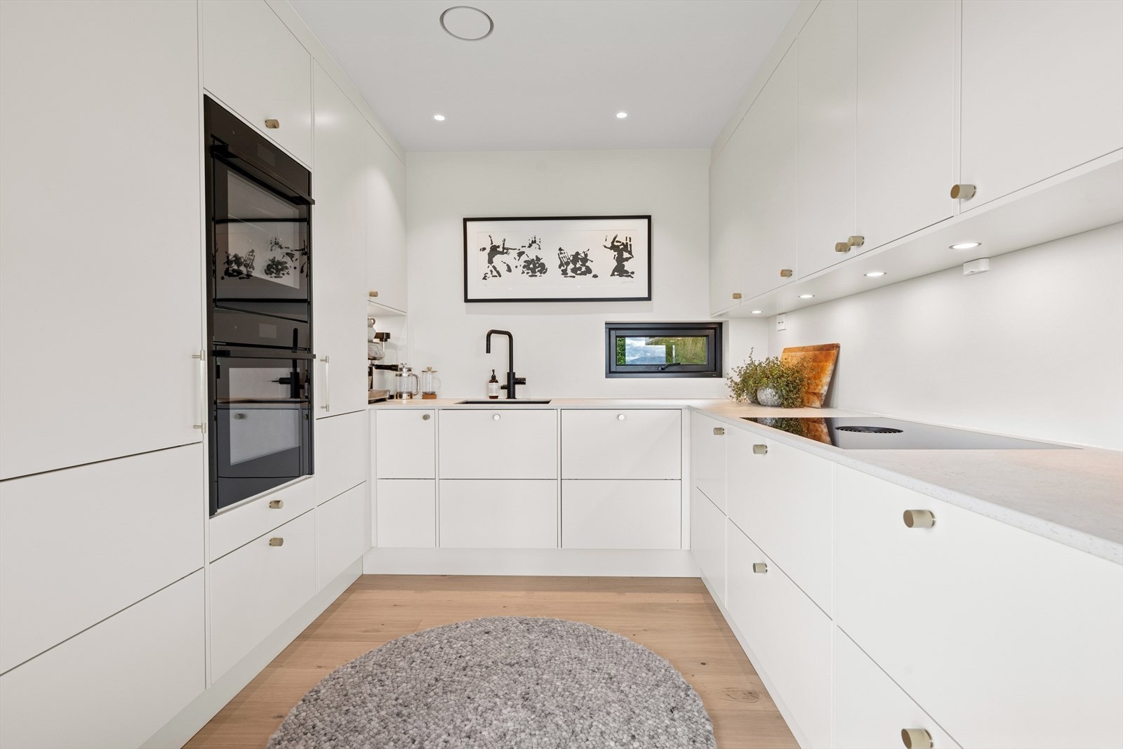 Kjøkkenet har en stilren og tidsriktig innredning med lyse slette fronter, takhøyde fronter og benkeplate i kompositt Galleribilde