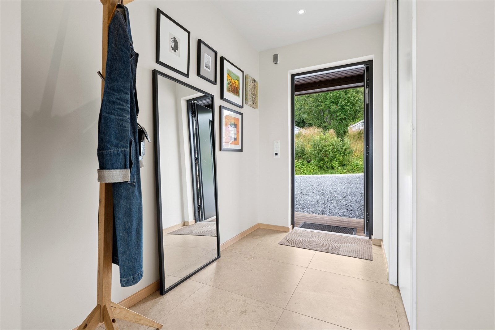 Du ønskes velkommen inn i en hyggelig entrè utført med moderne fliser på gulvet, slette overflater og downlights Galleribilde