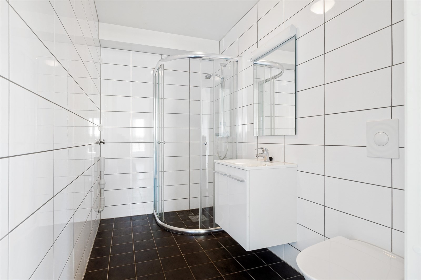 Flott bad med flislagte vegger og gulv. Det inneholder dusjhjørne, servant med underskap, toalett og opplegg til vaskemaskin. Elektrisk gulvvarme. Galleribilde