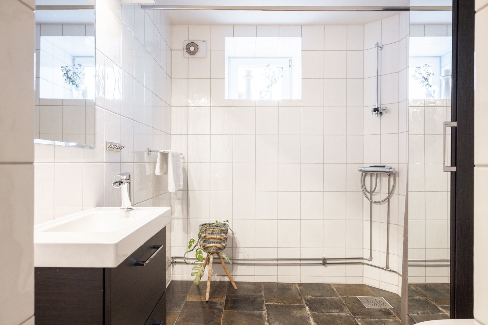 Romslig flislagt bad med varmekabler i gulvet. Innredningen består av servantskap med skuffer samt nedfelt servant, i tillegg til et vegghengt speil plassert over servanten. Videre er det dusjhjørne og toalett. Galleribilde